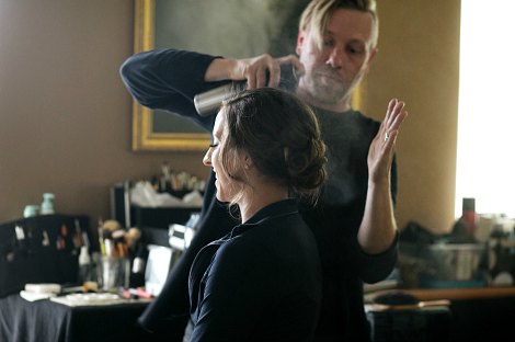 Stylist carefully hairsprays a bride during a trial run