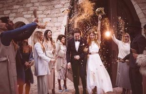 Wedding guests throw rice and flowers at a newly-wedded couple as they exit the church