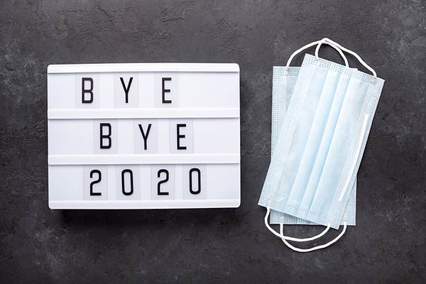 Lightbox with text BYE BYE 2020 with medical mask on dark background